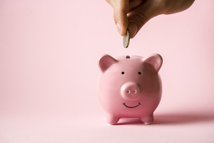 person dropping a coin into a fintech piggy bank