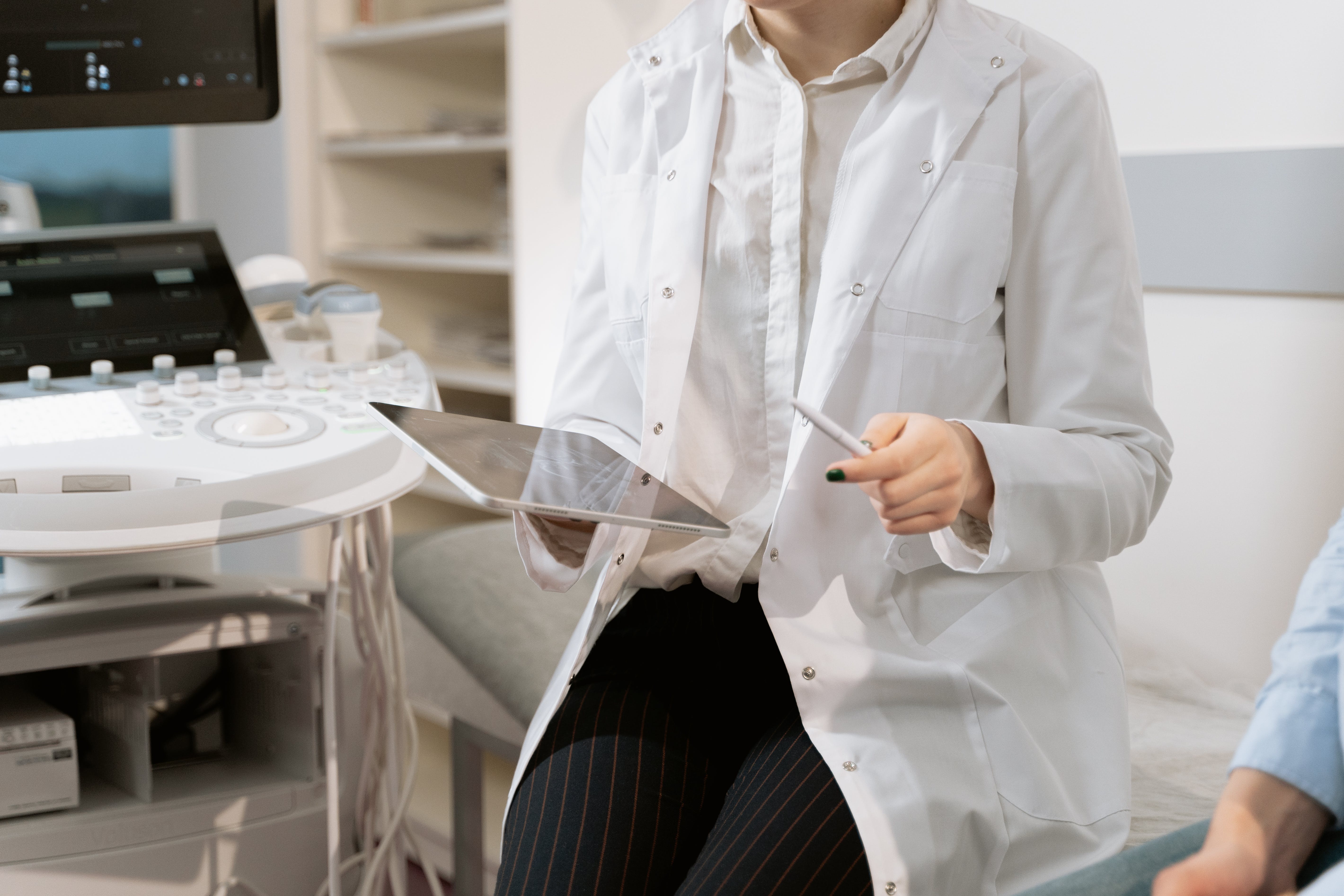 doctor sitting on stool holding an ipad