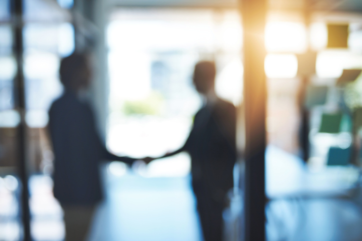 blurry image of people shaking hands during an M&A