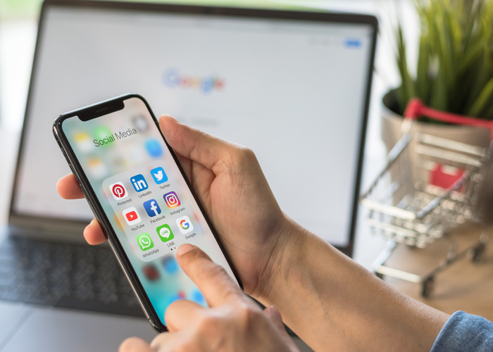 someone holding a phone with social media apps on the screen