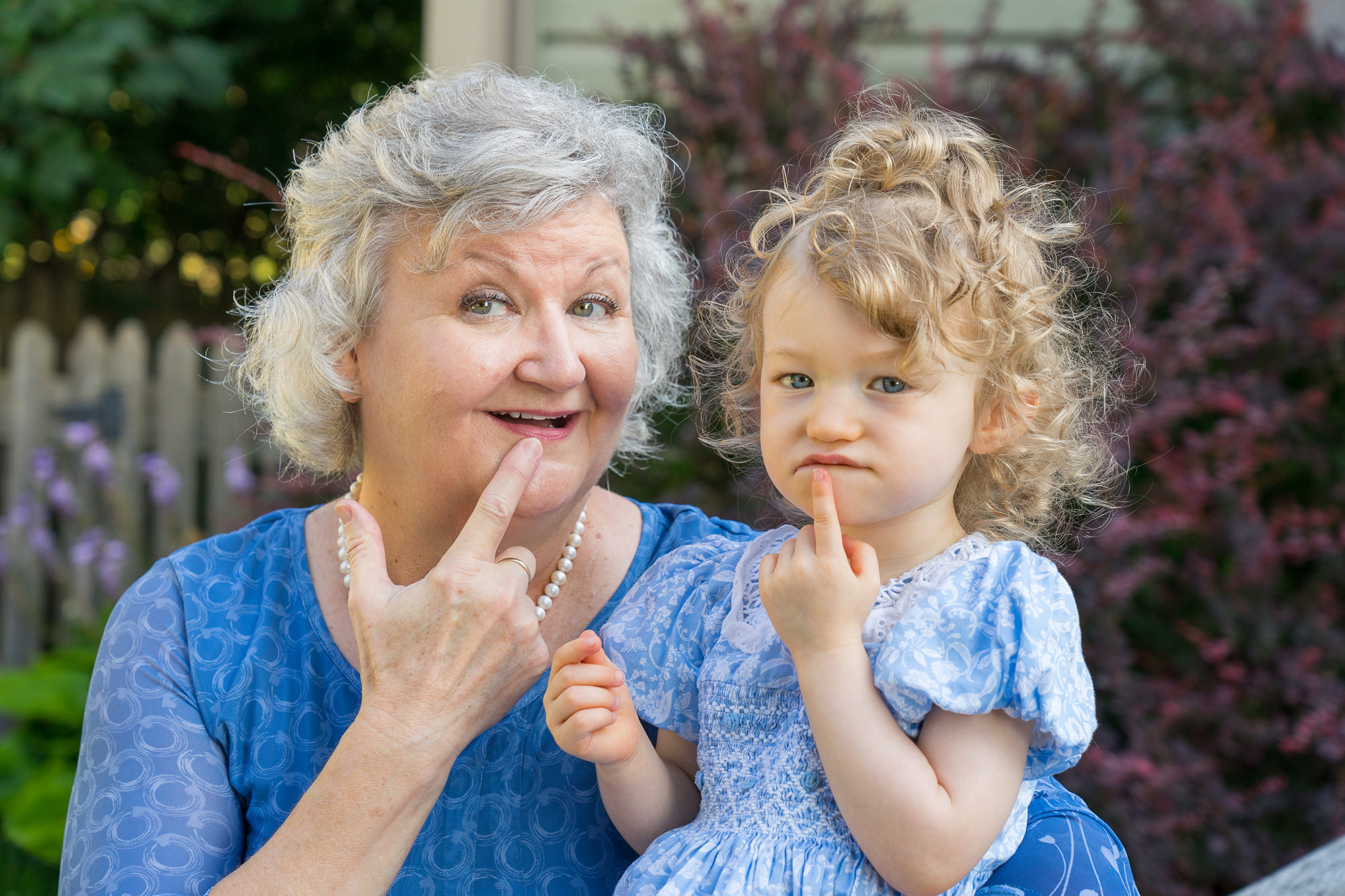 Grandma and grandaughter, mimicing each other with fingers on their chins