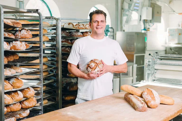 Bäckermeister Alexander Moucka der INTERSPAR-Bäckerei lächelt mit seinem Bäckerliebling in die Kamera