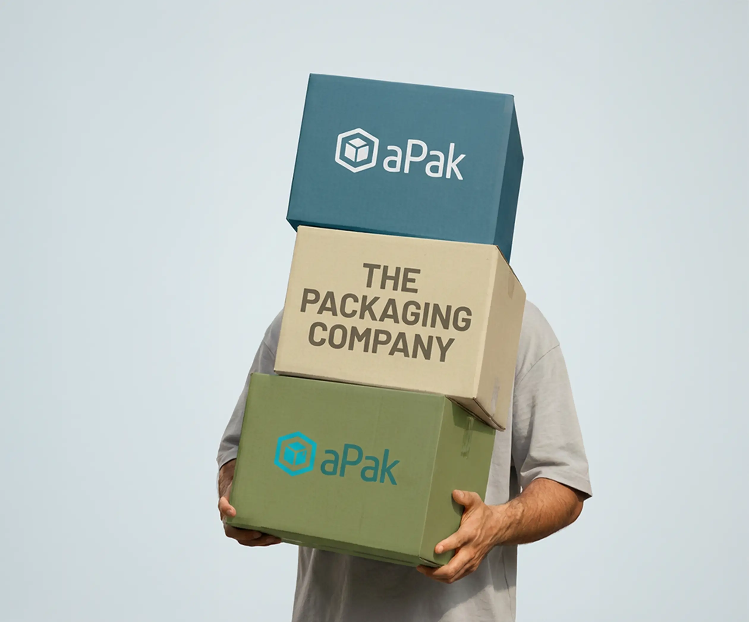 Person holding three stacked boxes, each labeled "aPak" and "The Packaging Company," against a light blue background.