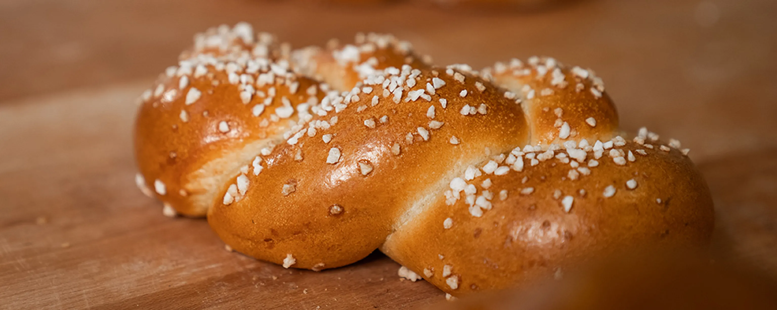 Ein frisch gebackener Bäckerstriezel mit Hagelzucker aus der INTERSPAR-Bäckerei auf einem Holzbrett
