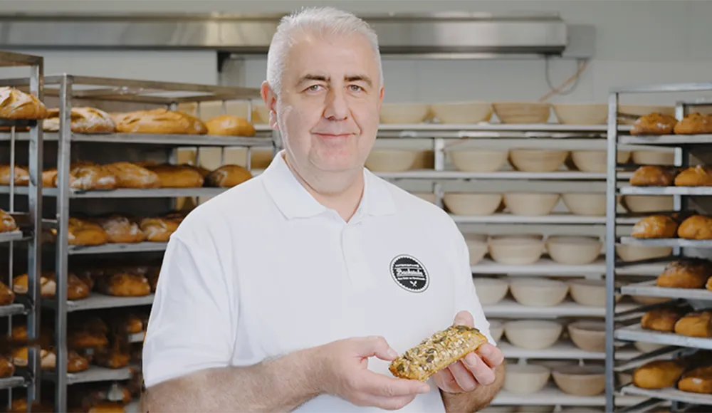 Handwerksbäcker Faruk Bisanovic der INTERSPAR-Bäckerei lächelt mit seinem Bäckerliebling in die Kamera
