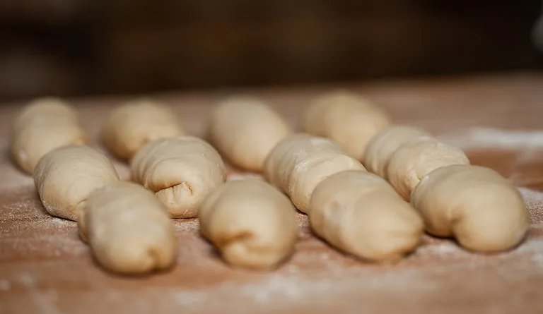 Mehrere portionierte Teiglinge aus Germteig auf einer bemehlten Fläche