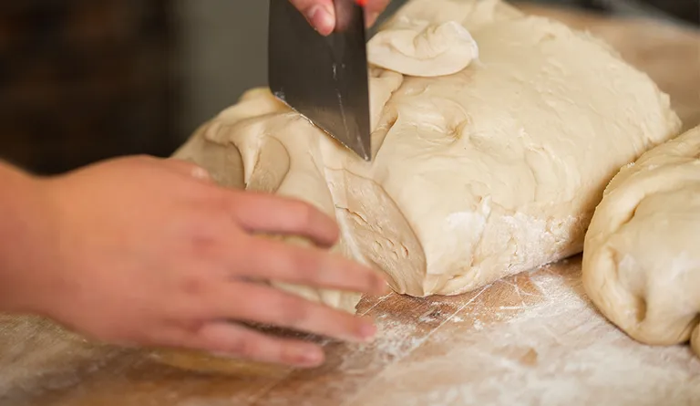 Eine Bäckerin beim Portionieren von einzelnen Germteig-Stücken