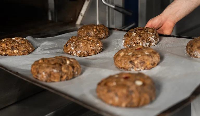 Mehrere frisch geformte Früchtebrote liegen auf einem großen Backblech