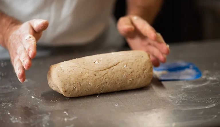 Ein Bäcker neben einem großen Teigklumpen für Vanillekipferl