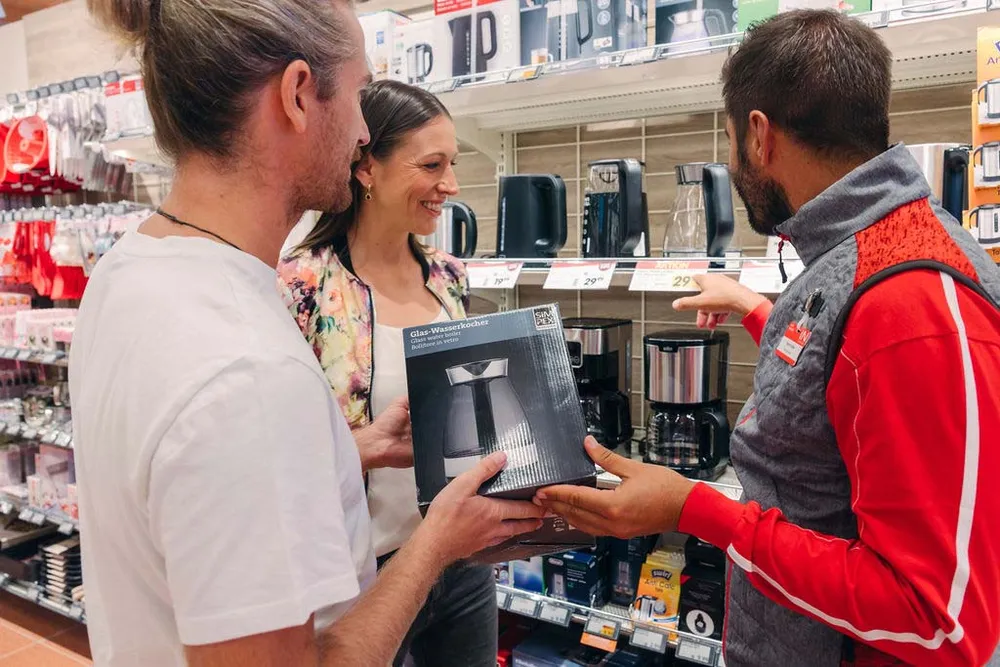 Mitarbeiter berät Kundinnen und Kunden beim Kauf eines Wasserkochers im INTERSPAR Markt