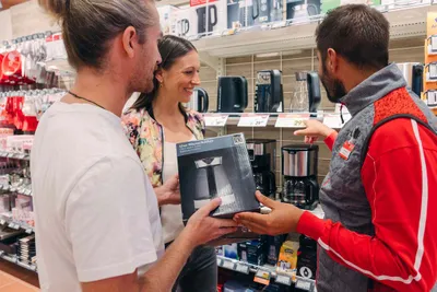 Mitarbeiter berät Kundinnen und Kunden beim Kauf eines Wasserkochers im INTERSPAR Markt