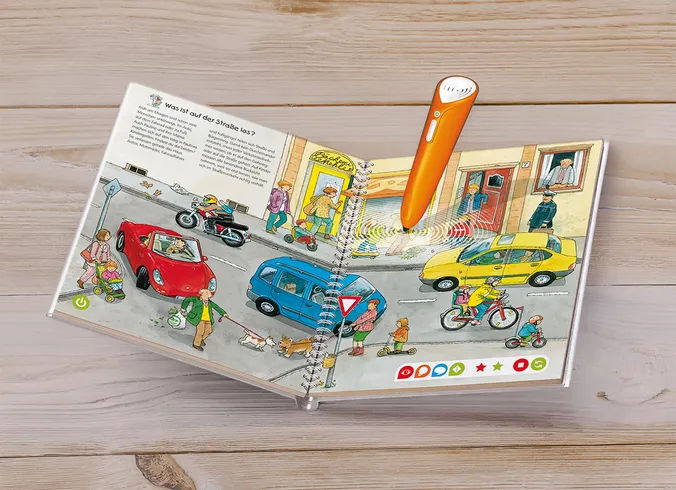 Ein tiptoi-Spielbuch inkl. Stift liegt auf dem Holzboden.