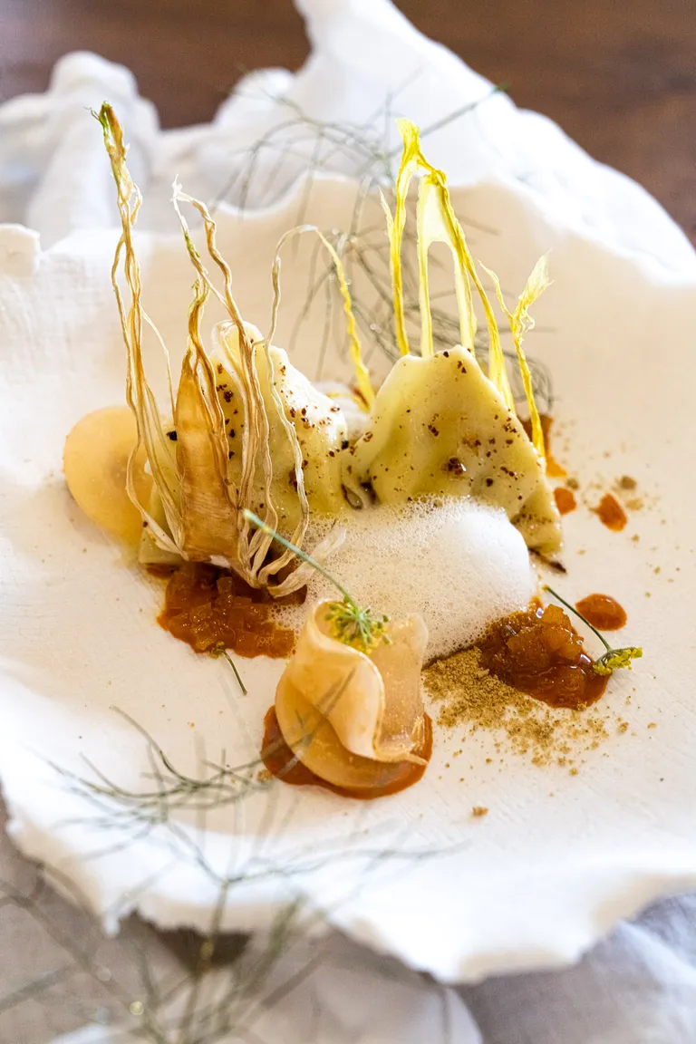 Feine Fencheltascherl mit hellem Sternanisschaum, Goldbeete und knusprigen Fenchelspitzen auf einem weißen Teller