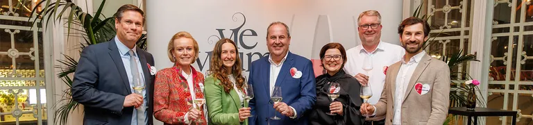Damen und Herren der Vievinum sowie INTERSPAR, lächeln in die Kamera und halten ein Glas Wein in der Hand