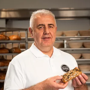 Handwerksbäcker Faruk Bisanovic der INTERSPAR-Bäckerei lächelt mit seinem Bäckerliebling in die Kamera