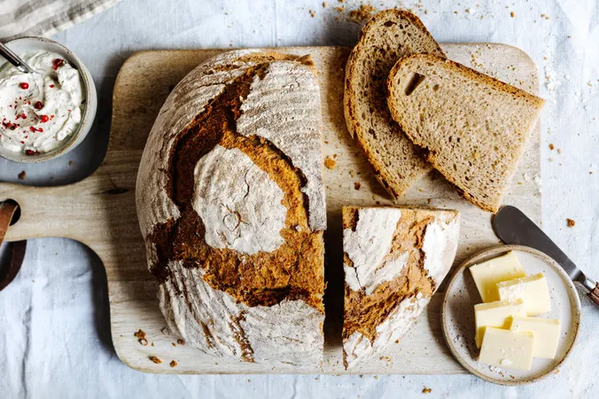 Aufgeschnittenes Brot auf Holzbrett mit Butter, Ansicht von oben