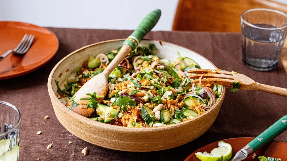 Crispy Rice Salad in einer Schüssel angerichtet mit Holz-Salatbesteck, auf einem Tisch