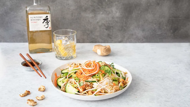 Reisnudelsalat mit Gurke, Karotten, Frühlingszwiebeln und Cashewkernen auf einem Teller