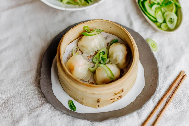 Gedämpfte Garnelen-Dim-Sum in einem Bambusdämpfer mit Frühlingszwiebeln