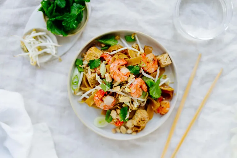Pad Thai mit Reisbandnudeln, Garnelen, Tofu, Erdnüssen und frischen Kräutern
