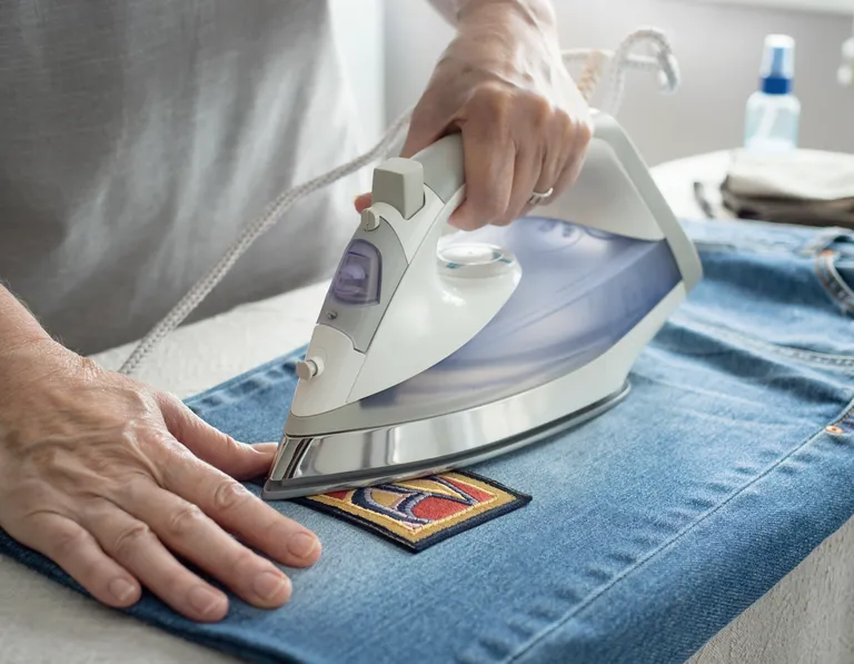 hände bügeln einen bügelpatch auf einn paar jeans