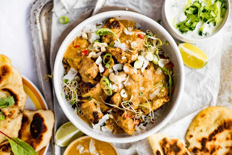 Cremiges Butter Chicken mit Reis, Naan-Brot und frischen Kräutern
