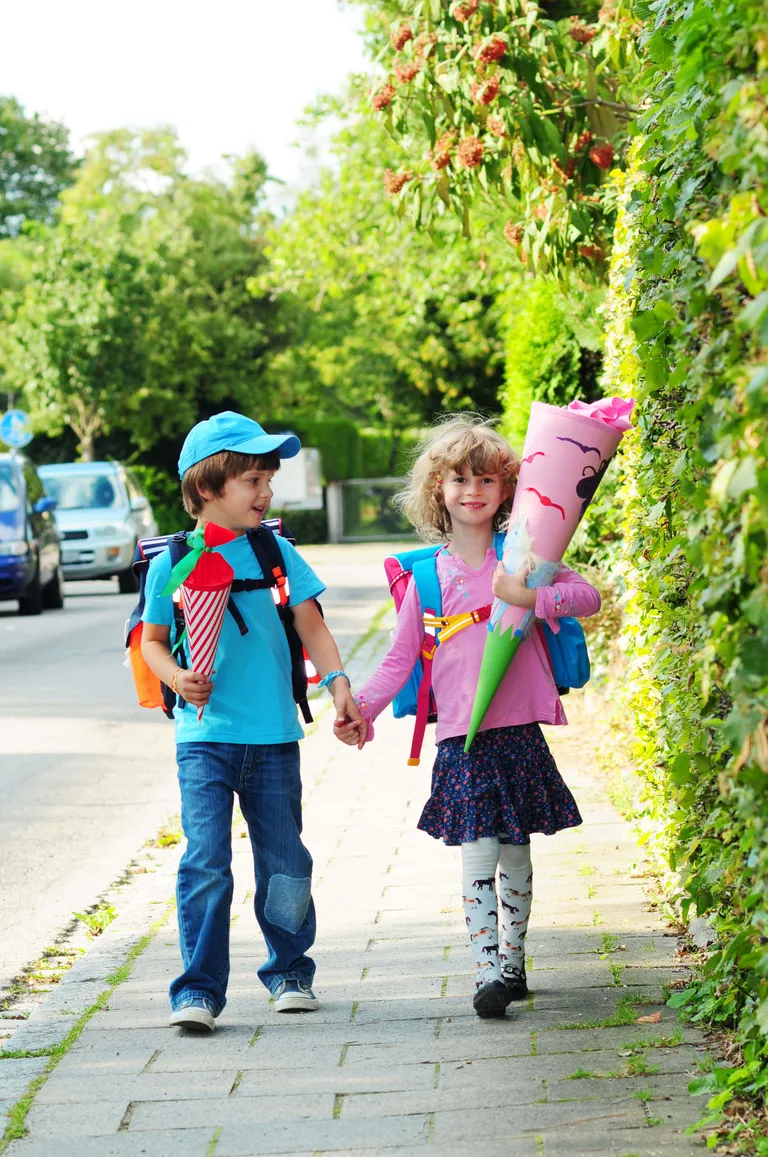 Junge und Mädchen gehen mit Schultüten und Schulrucksäcken zur Schule
