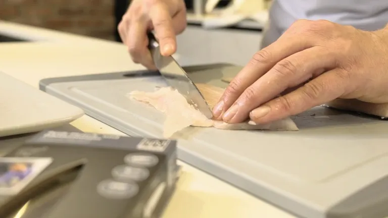 Eine Person beim Schneiden eines frischen Fischfilets mit einem Fisch- und Fleischmesser