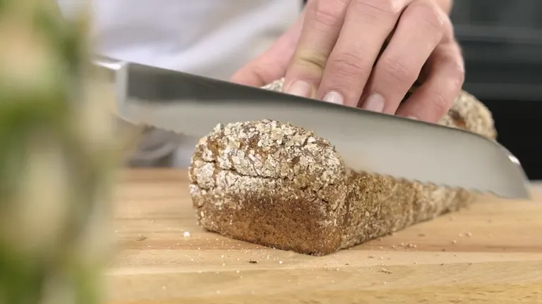 Eine Person beim Schneiden eines Brotlaibs mit einem Brotmesser