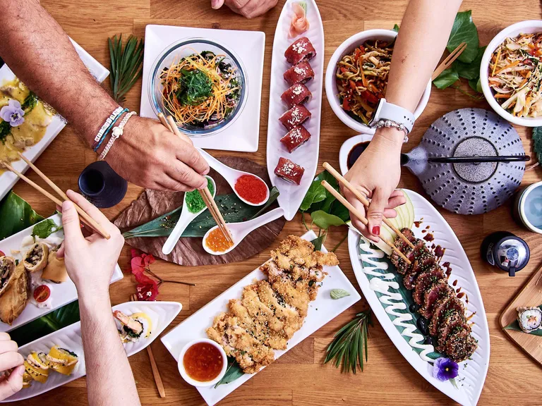 Gemeinsames asiatisches Essen mit verschiedenen asiatischen Spezialitäten auf einem reich gedeckten Tisch