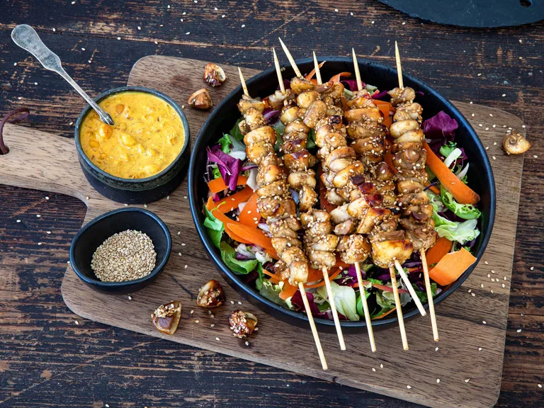 Mehrere frisch gegrillte Champignon-Spieße auf einer Gemüsepfanne