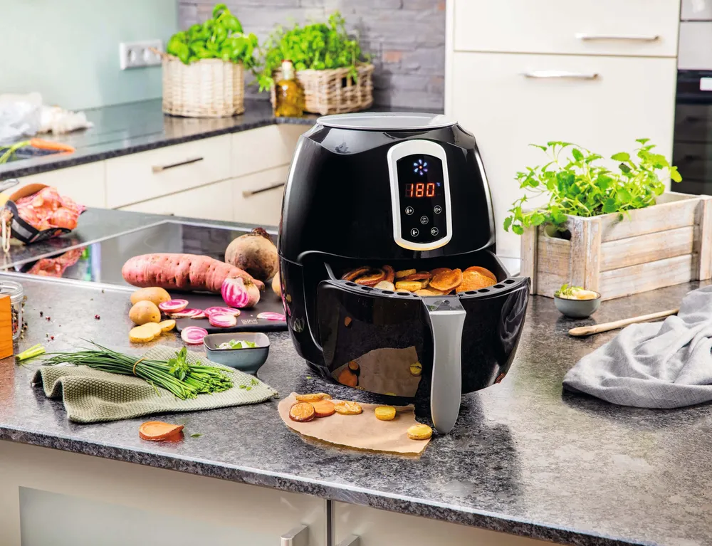 Heißluftfritteuse bereitet Gemüsechips aus Süßkartoffeln, Kartoffeln und Roter Rübe in einer modernen Küche zu