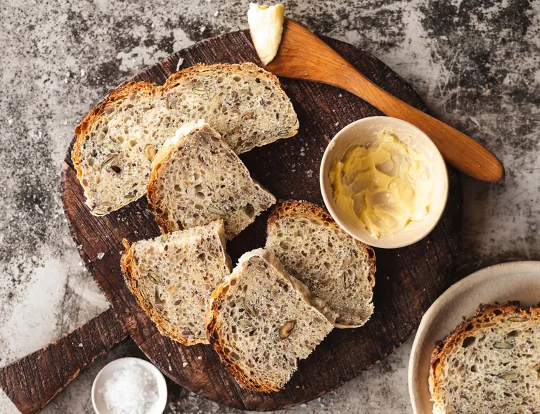 Frisch gebackenes Saatenbrot mit Butter auf einem Holzbrett aus der Heißluftfritteuse