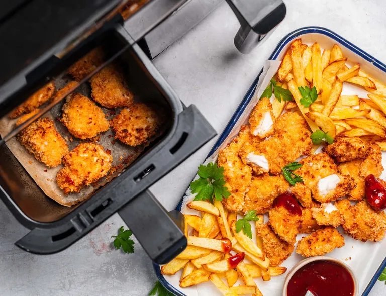 Knusprige Chicken Nuggets und Pommes frisch aus der Heißluftfritteuse mit Dip serviert