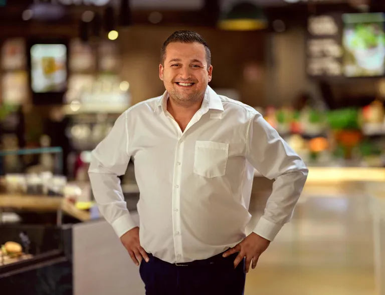 Mitarbeiter im INTERSPAR-Restaurant steht lächelnd im Gästebereich