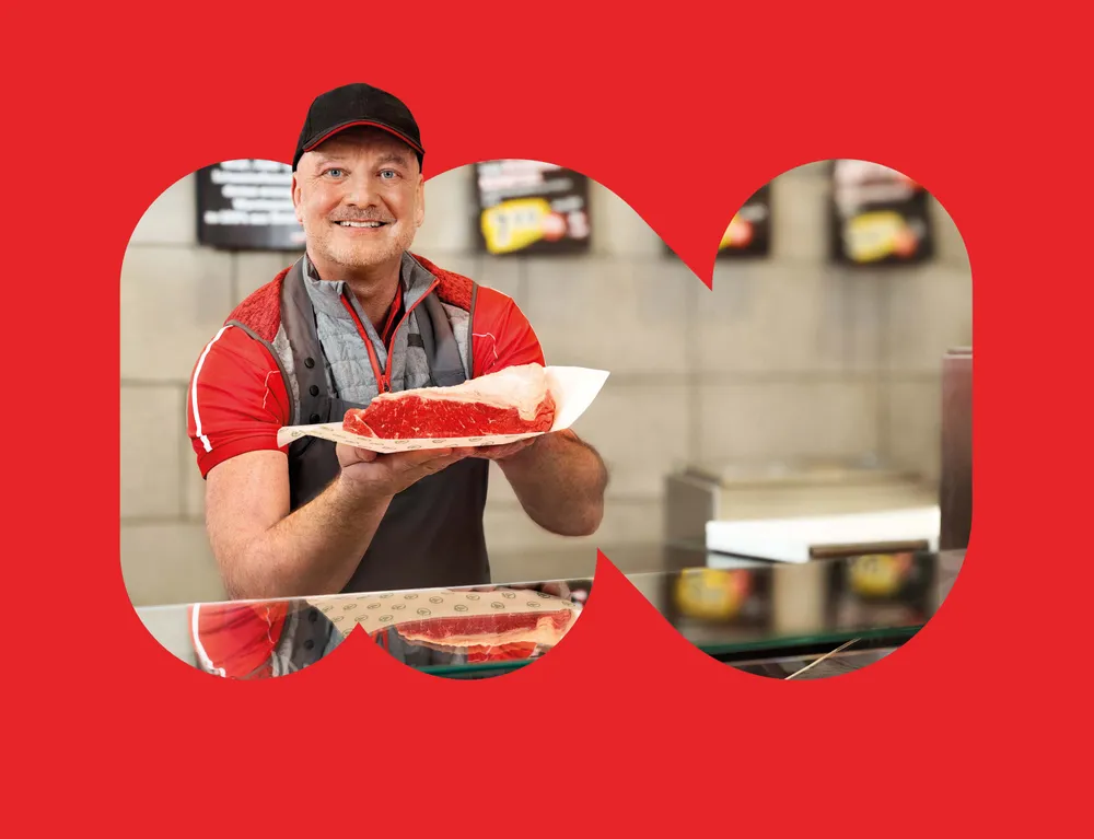 TANN Mitarbeiter präsentiert frisches Fleisch an der Fleischtheke im INTERSPAR Markt
