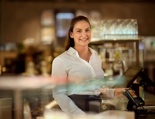 Mitarbeiterin im INTERSPAR-Restaurant steht an der Kassa hinter der Theke