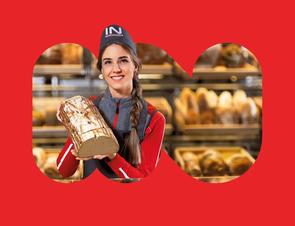 INTERSPAR Mitarbeiterin präsentiert frisches Brot vor der Backwarenabteilung