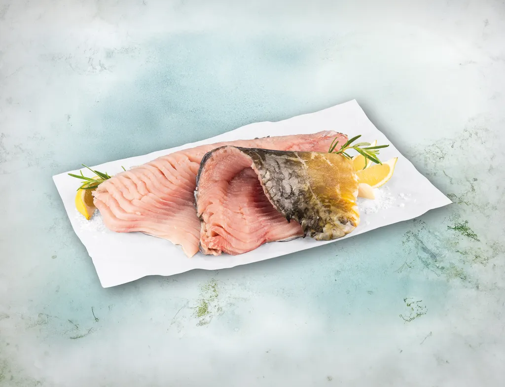 Zwei Karpfenfilets liegen neben etwas Salz und Zitronenscheiben auf einem hellen Stück Papier