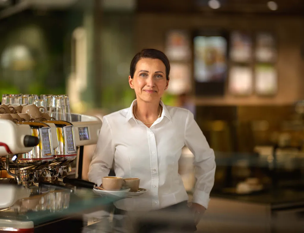 Mitarbeiterin im INTERSPAR-Restaurant steht mit Kaffee an der Kaffeemaschine