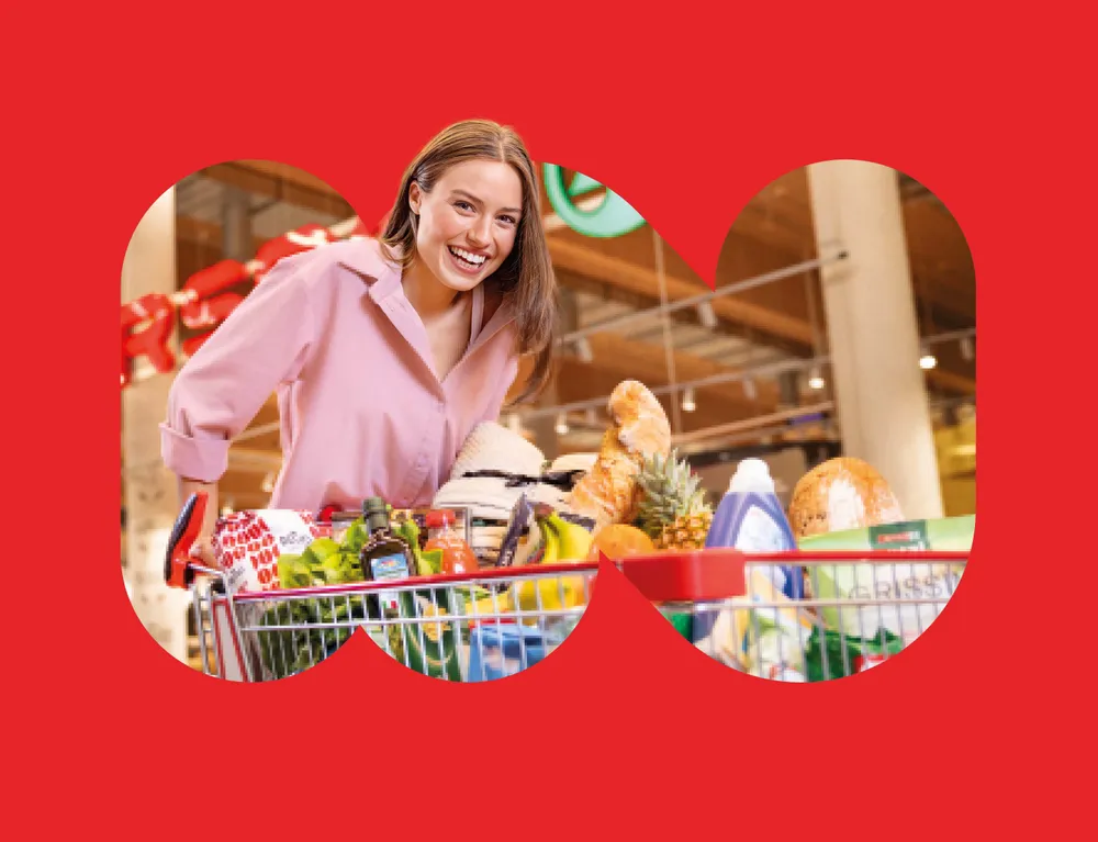 Lachende Kundin mit gefülltem Einkaufswagen beim Einkauf im INTERSPAR Markt