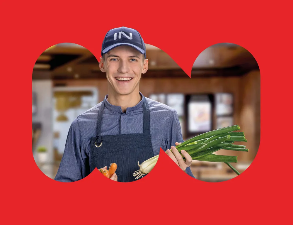 INTERSPAR Restaurant Mitarbeiter präsentiert Karotten und Frühlingszwiebeln