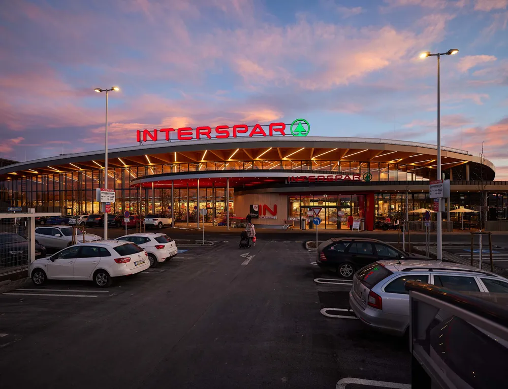 Außenansicht eines modernen INTERSPAR-Hypermarkts mit beleuchtetem Eingang und Parkplatz