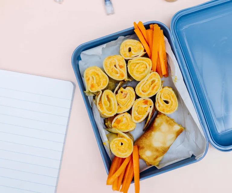 Aufgeschnittene Omelett-Wraps mit Karotten in einer Lunchbox als gesunder Snack