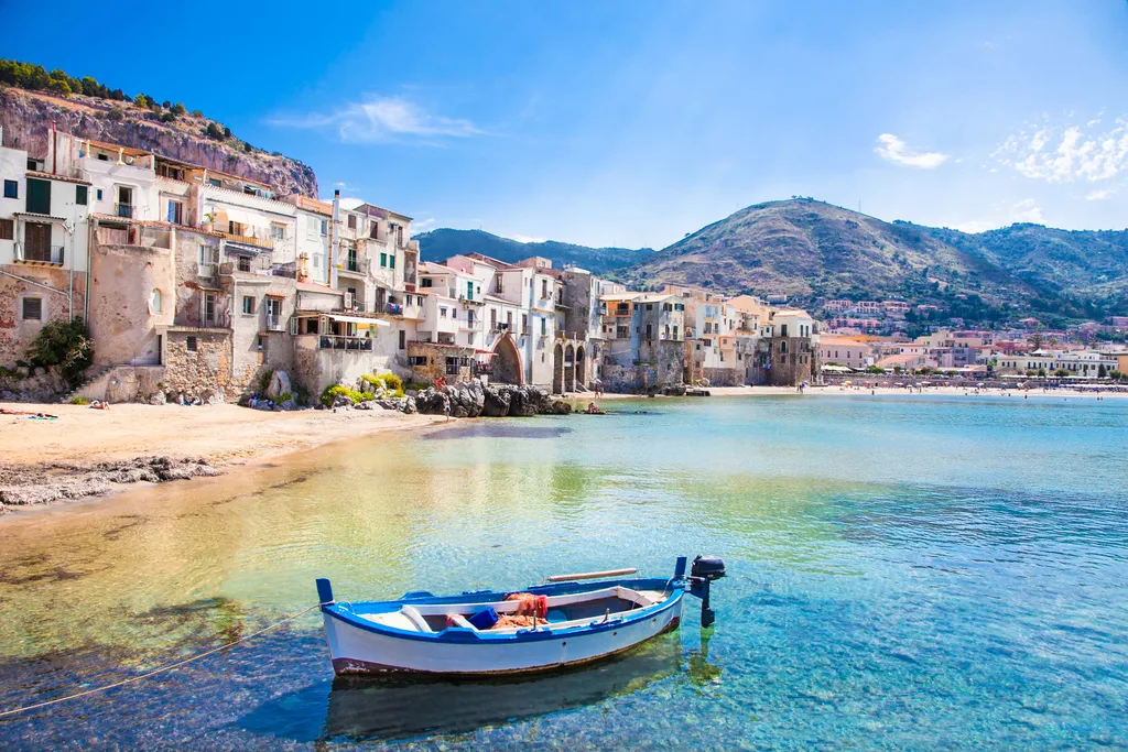Küstenstadt Cefalù auf Sizilien mit Sandstrand, Fischerboot und kristallklarem Meer