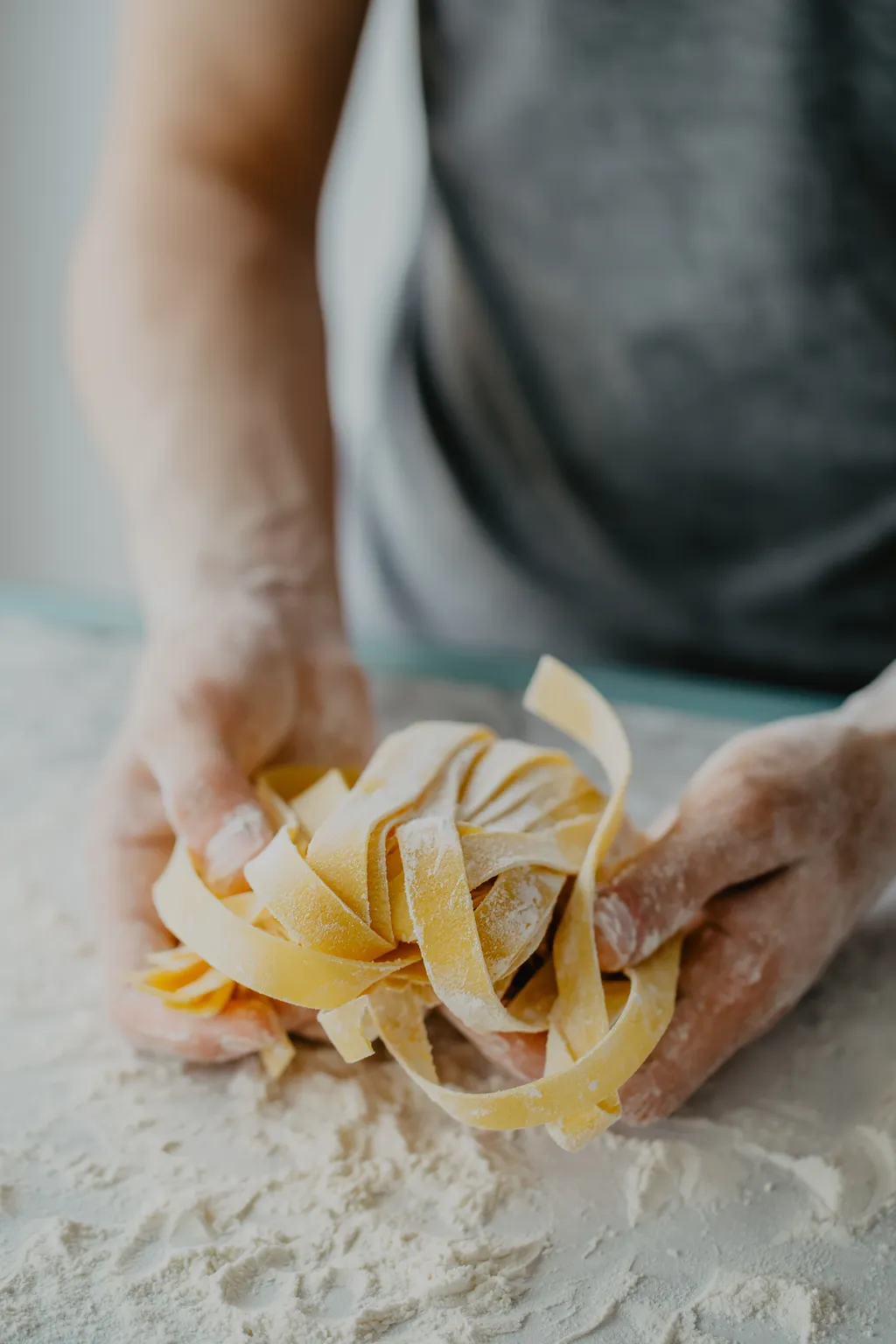 Eine Person macht Pasta selbst, hält Nudeln in den Händen