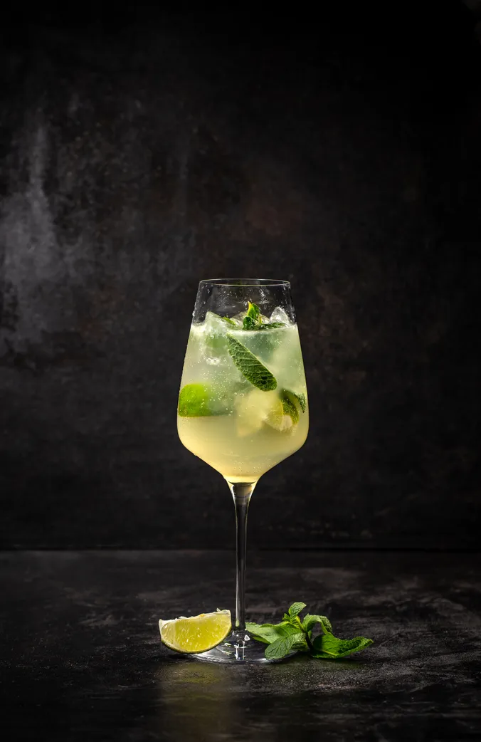 Ein Glas Hugo steht vor einer schwarzen Wand.