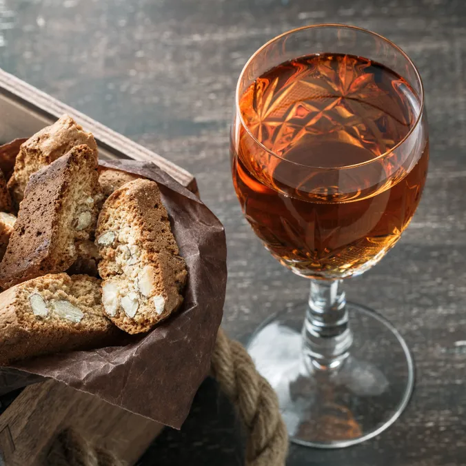Ein Glas Wein steht neben einem süßen Gebäck.