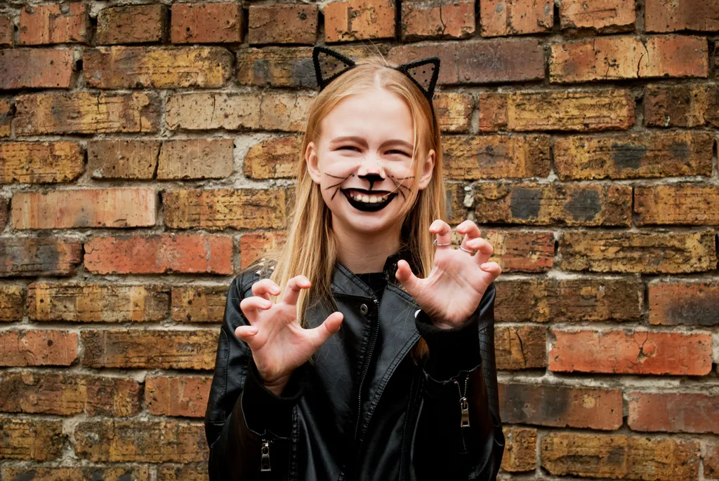 Frau verkleidet als Katze vor Ziegelwand