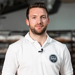 Handwerksbäcker Patrick Beschta der INTERSPAR-Bäckerei lächelt mit seinem Bäckerliebling in die Kamera